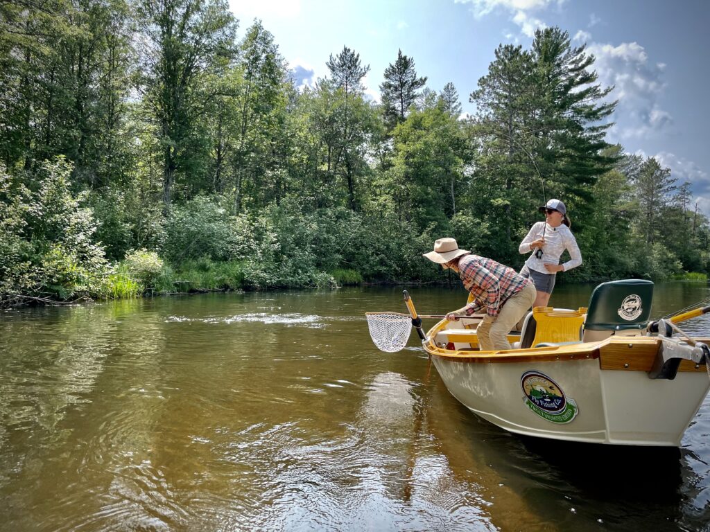 An angler battles a summer smallmouth from a guide boat 

